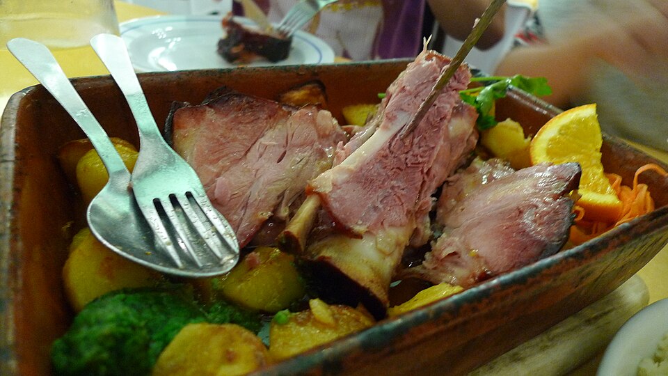 Wood-roasted pork shank served in a roasting dish at Antunes in Porto.