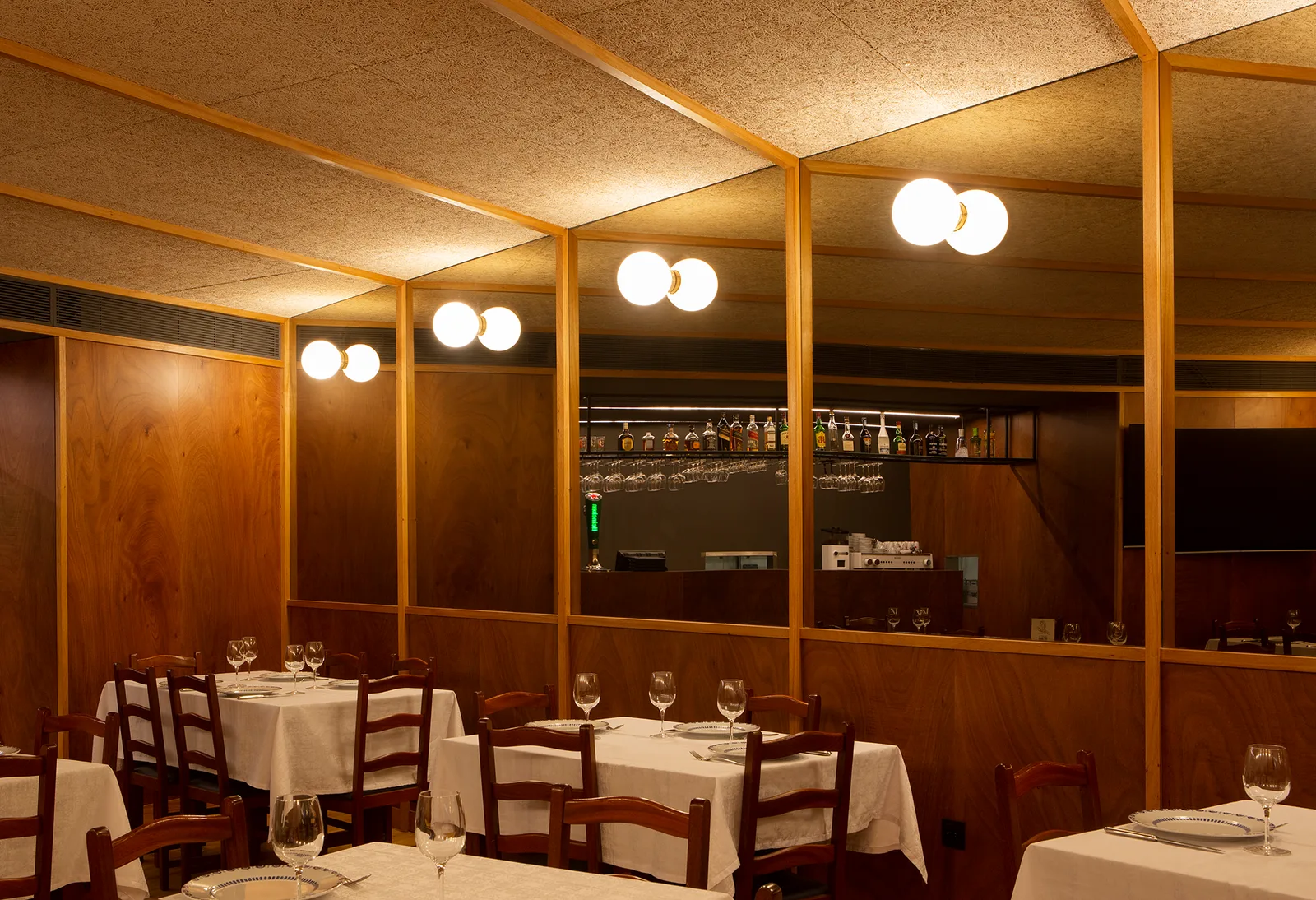 The dining room at Casa Nanda in Porto, with wood panelling, mirrors, and white-clothed tables.