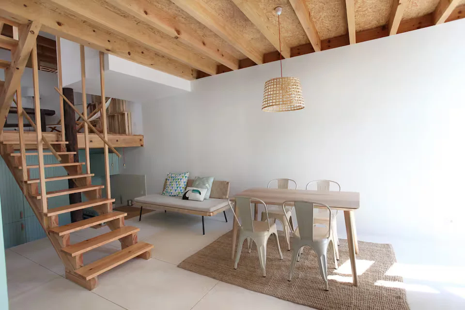 Open wooden staircase, exposed beams and dining table at Wood & Blue House.