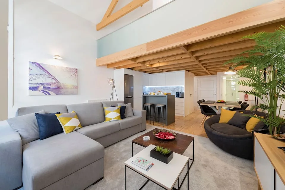 Living room with a grey sofa beneath the wooden mezzanine in the Aliados loft.