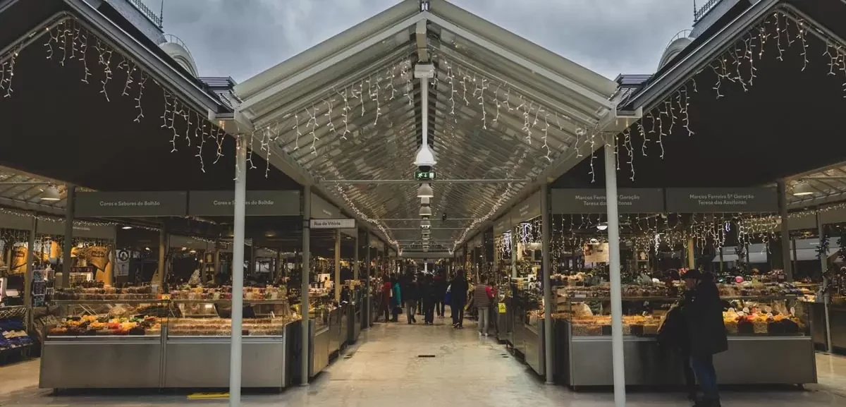 Covered aisle inside Mercado do Bolhao with food stalls on both sides.
